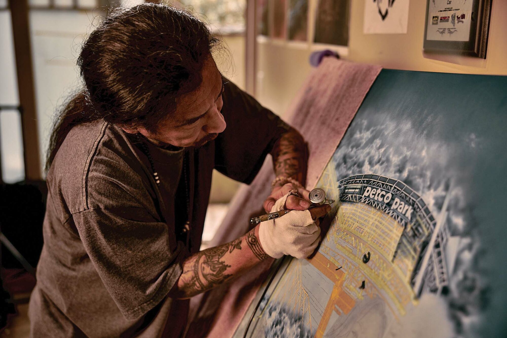 Masonic lowrider artist Shinji Hara of Anaheim no. 207 works on a new airbrush piece in his home.