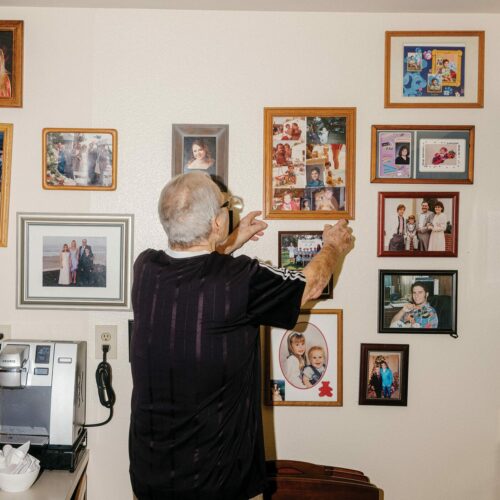 Resident David Thompson hangs photos on the wall of his apartment at the Masonic Homes of California.