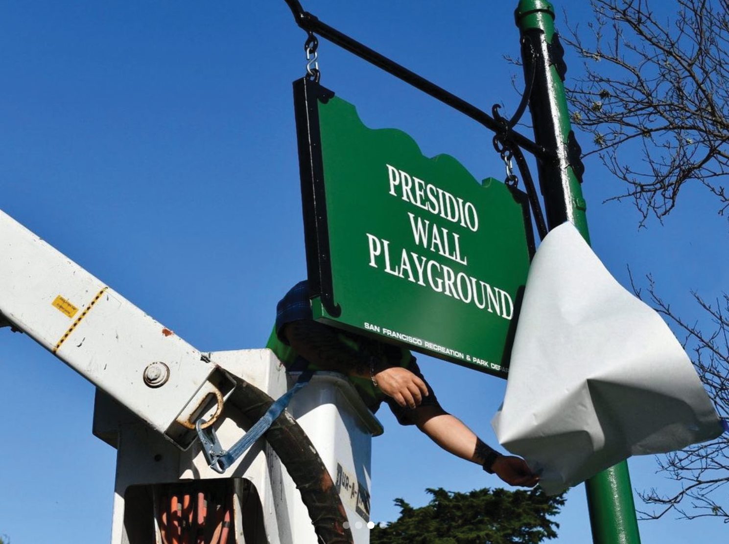 Workers unveil the new sign for Presidio Wall Playground, formerly Julius Kahn Playground.